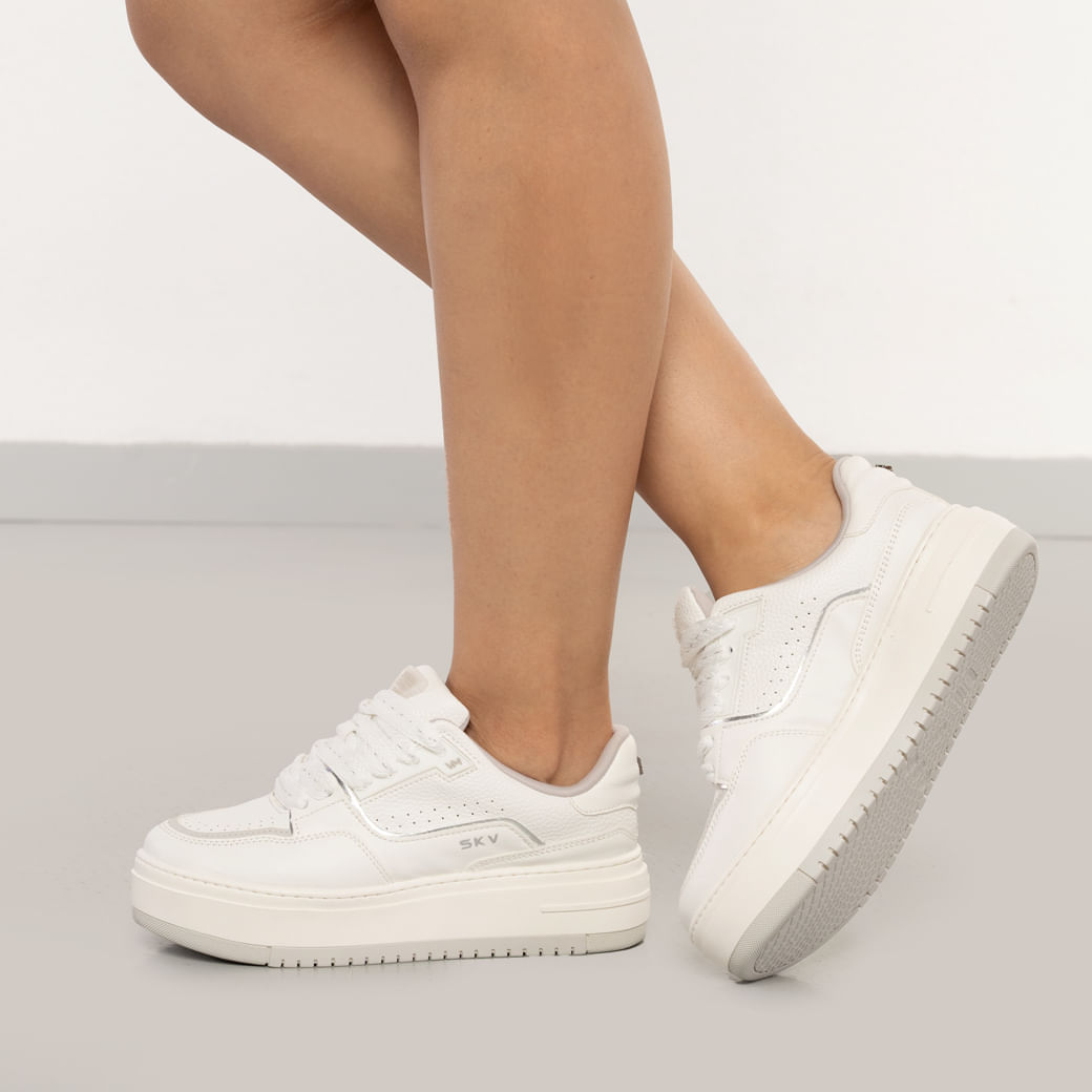 Tênis casual feminino branco com detalhes prata e solado grosso branco visto de lado